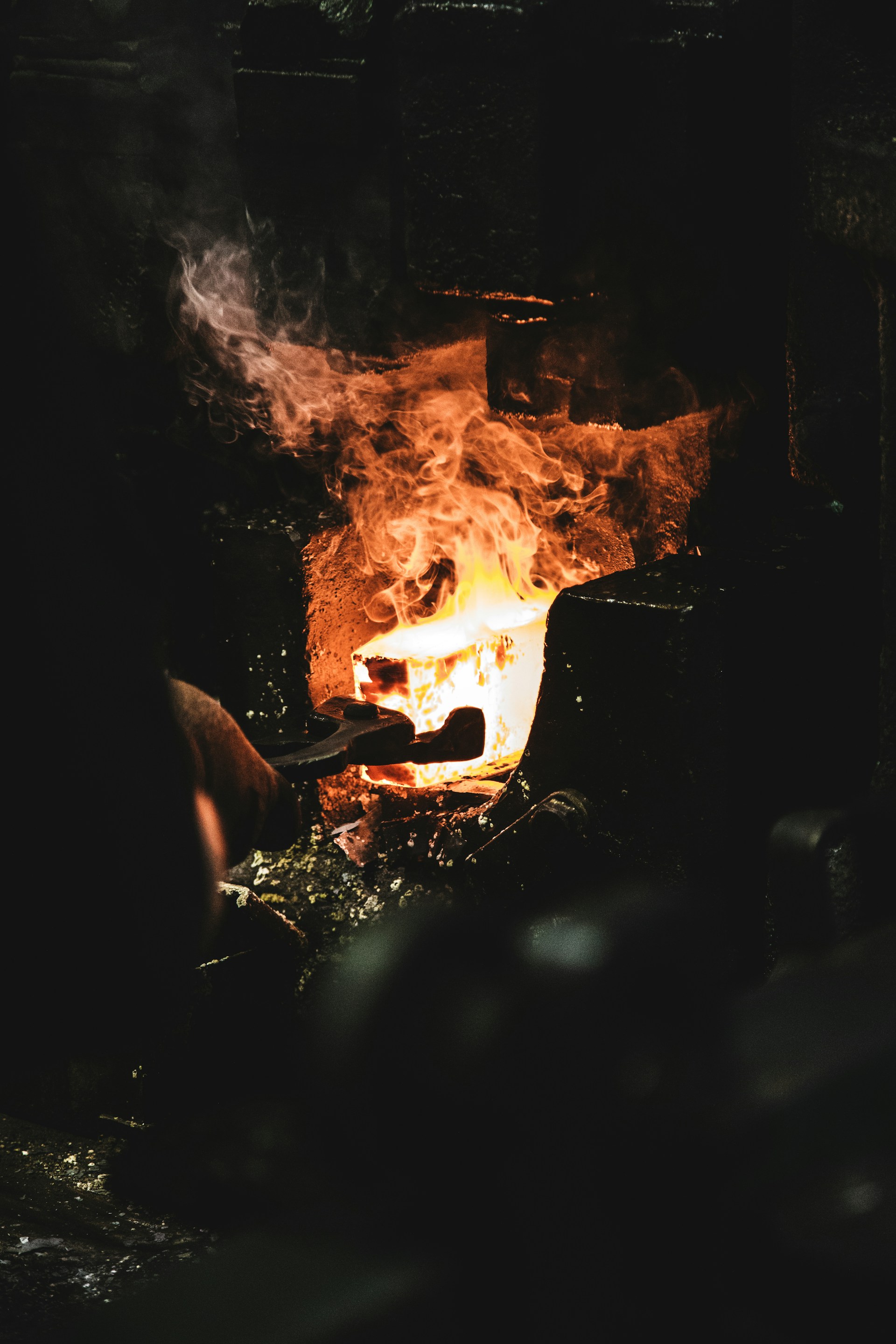 Blacksmith placing raw metal into an industrial forge, symbolizing disciplined transformation under pressure